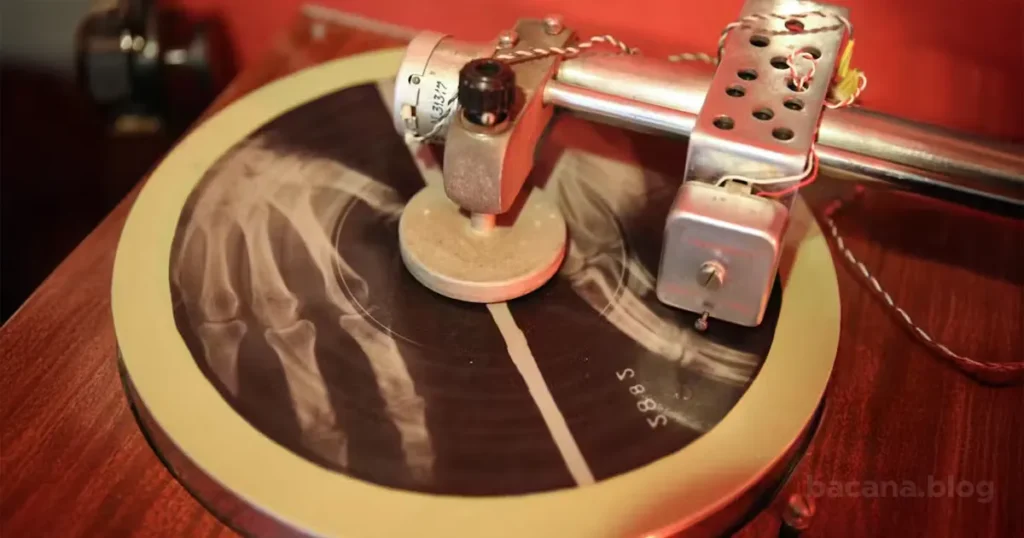 Foto de um torno mecânico de gravação vintage cortando sulcos musicais em uma chapa de raio‑X (“disco de osso”)